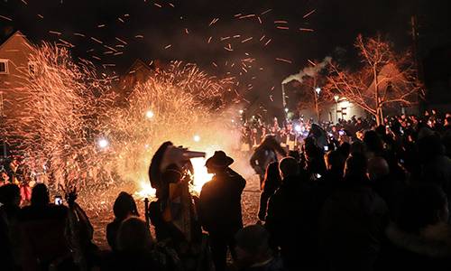 Dicht umringt von den Zuschauern springen die als Pferde verkleideten Männer samt Pflug durch die Flammen © Heike Hickmann Dicht umringt von den Zuschauern springen die als Pferde verkleideten Männer samt Pflug durch die Flammen © Heike Hickmann